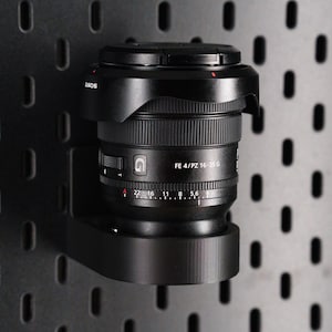 May include: A black Sony FE 4/PZ 16-35 G lens with a lens hood attached. The lens has a depth of field scale and aperture ring.