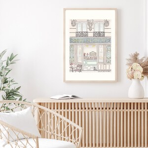 May include: A watercolor illustration of a Parisian bakery storefront with a blue sign that reads "BOULANGERIE". The bakery has a large window with a view of the interior, and there is a small table and chair outside.