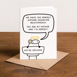 Peut inclure: Carte de v&oelig;ux blanche avec un personnage de dessin anim&eacute; tenant une pancarte avec l'inscription "YOU'RE WELCOME". La carte comporte une bulle de dialogue avec le texte : "WE HAVE THE PERFECT MOTHER-DAUGHTER RELATIONSHIP. YOU ARE MY MOTHER AND I'M PERFECT."