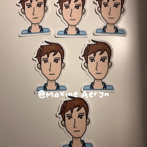 Op de afbeelding: Zes stickers met een cartoon illustratie van een persoon met bruin haar, sproeten en een blauw shirt. De stickers zijn gerangschikt op een wit oppervlak. De tekst "@Maxine Aeryn" is zichtbaar.
