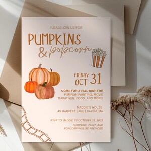 May include: A fall-themed invitation with the text "Pumpkins & Popcorn" and a watercolor illustration of pumpkins and popcorn. The invitation includes the date "Friday, Oct 31" and event details. The invitation is on a cream background.