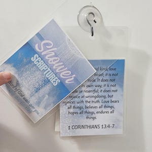 Peut inclure: Cartes de douche en plastique transparent avec les mots "Shower Scriptures" dans un design bleu et blanc. La carte comprend un verset biblique de 1 Corinthiens 13:4-7. Les cartes sont fixées au mur avec une ventouse.