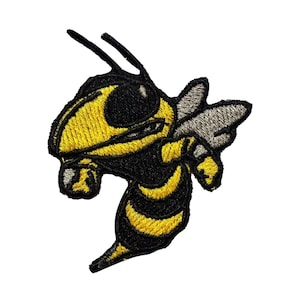 May include: Embroidered patch featuring a stylized yellow and black hornet. The hornet is depicted in a dynamic pose with its wings slightly spread. The patch has a detailed design with a textured appearance, suitable for application on clothing or accessories.