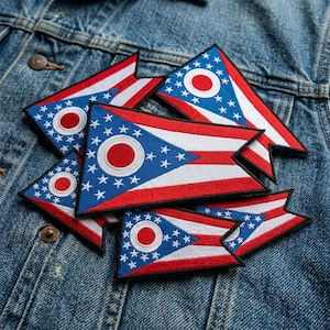 May include: A collection of embroidered swallowtail patches featuring the Ohio state flag design. Each patch displays a blue triangle with white stars and a red circle, alongside red and white horizontal stripes, all with a black stitched border.