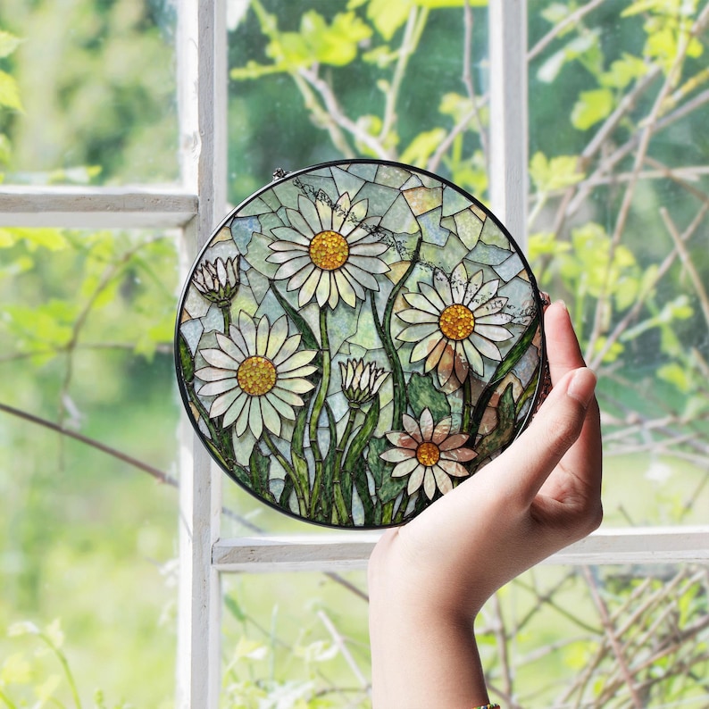 a hand holding a stained glass plate with daisies on it