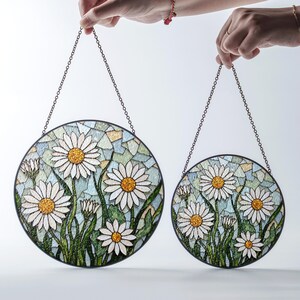 a hand holding a pair of stained glass sun catchers