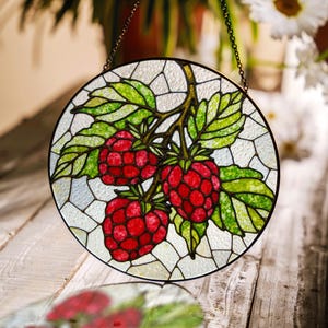 May include: A stained glass window hanging with a chain, depicting a branch of raspberries with green leaves. The raspberries are red and have a detailed, mosaic-like design.