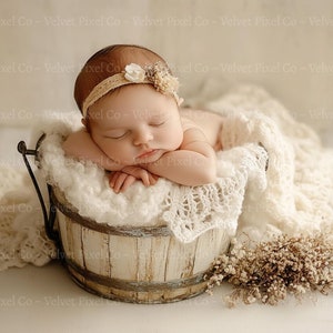 Könnte beinhalten: Ein neugeborenes Baby schläft in einem weißen gehäkelten Eimer mit einem weißen Blumenhaarband. Der Eimer steht auf einer weißen Oberfläche mit getrockneten Blumen.