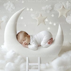May include: A newborn baby sleeping on a white crescent moon prop surrounded by white fluffy clouds and stars.