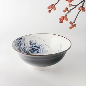 May include: A large white ceramic bowl with a blue and white wave design. The bowl has a black rim and a black stripe around the bottom.