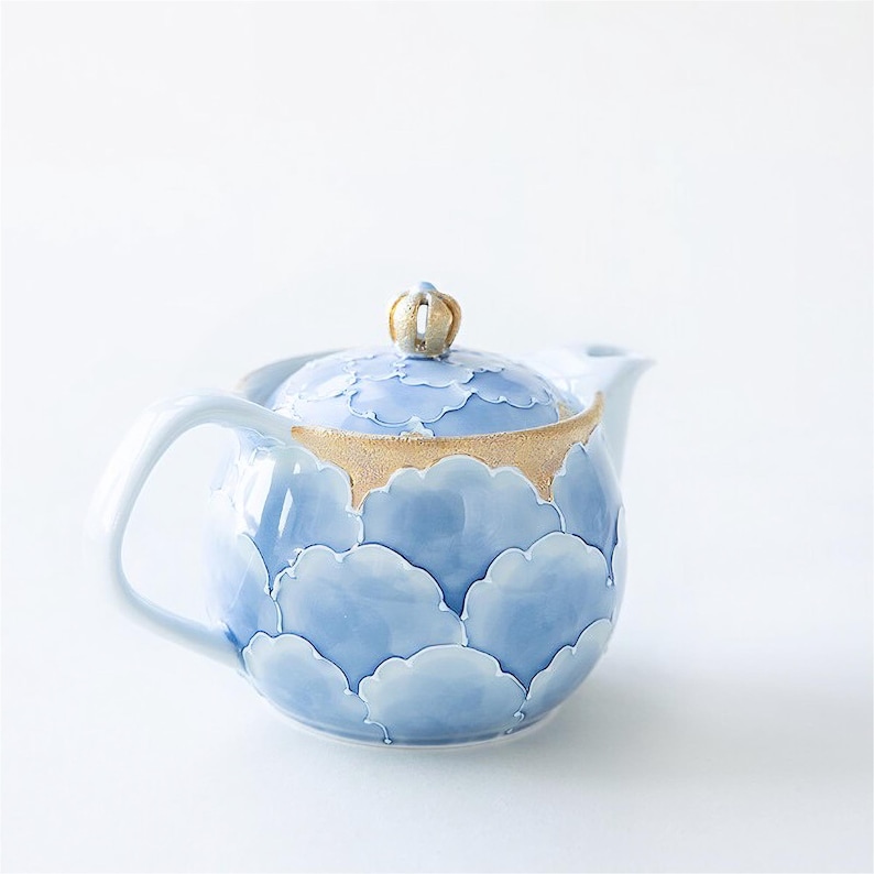 May include: A blue and gold ceramic teapot with a cloud pattern. The teapot has a lid with a small knob on top.