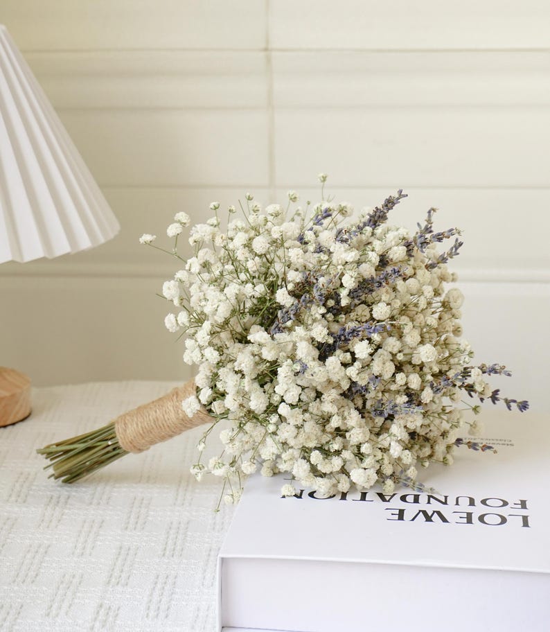 May include: A bridal bouquet made of white baby's breath and purple lavender flowers tied with twine.