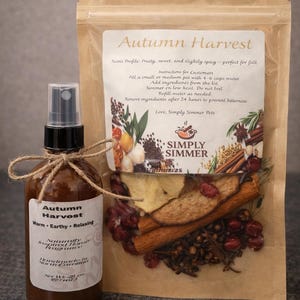 Puede incluir: Un juego de fragancia para el hogar Autumn Harvest. El juego incluye un frasco rociador de vidrio marrón con una etiqueta y una bolsa de papel kraft llena de especias secas. La etiqueta dice "Autumn Harvest" y "Warm, Earthy, Relaxing".