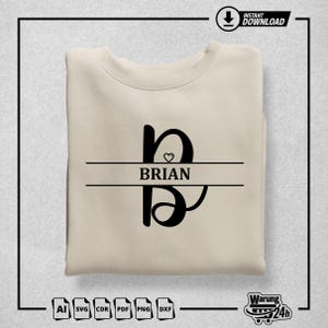 May include: A beige sweatshirt with a black letter B and the name "BRIAN" printed on it. The letter B has a small heart inside it.