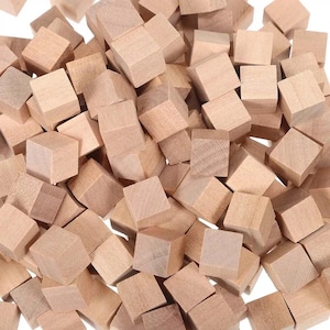Può includere: Un mucchio di piccoli cubi di legno non rifiniti. Ogni cubo ha un colore legno naturale e una consistenza leggermente ruvida. I cubi sono sparsi, suggerendo un uso artigianale o educativo.