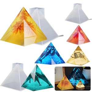 May include: A selection of pyramid-shaped resin art and moulds. The finished pieces have embedded designs of flowers, dolphins, and butterflies. The moulds are clear, while the art pieces display vibrant colours like yellow, blue, and orange.