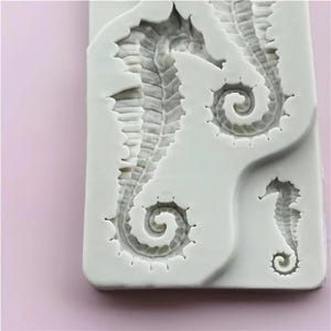 Pu&ograve; includere: Uno stampo in silicone bianco con tre disegni di cavallucci marini. I cavallucci marini hanno trame dettagliate e code arricciate. Lo stampo &egrave; rettangolare con angoli arrotondati, perfetto per creare oggetti artigianali o decorazioni a tema marino.