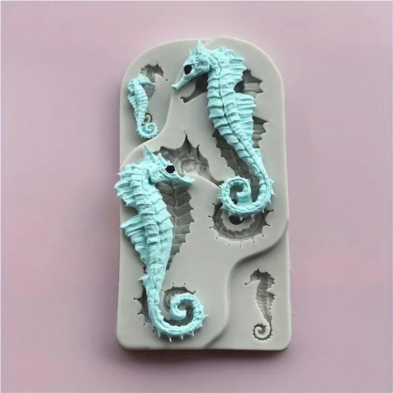Pu&ograve; includere: Uno stampo in silicone azzurro con tre disegni di cavallucci marini di varie dimensioni. I cavallucci marini presentano dettagli precisi e sono su uno sfondo grigio. Lo stampo &egrave; progettato per l'artigianato o la cottura, con un tema marino.
