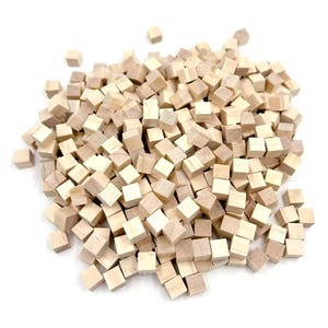 May include: A pile of small, unfinished wooden cubes. The cubes are a light, natural wood color and appear to be uniform in size. They are scattered on a white background, suggesting a craft or building material.