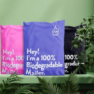 Könnte beinhalten: Drei farbige Versandtaschen: rosa, blau und schwarz. Auf der rosa Tasche steht "Hey! I'm a 100% Biodegradable Mailer." Auf der blauen Tasche steht "Hey! I'm a 100% Biodegradable Mailer." Auf der schwarzen Tasche steht "100% gradar r."