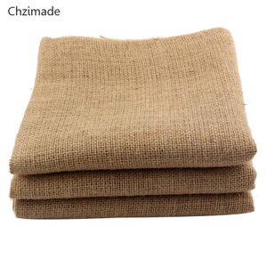 Pode incluir: Tecido de juta dobrado em tom castanho natural, empilhado. A trama grosseira do tecido é visível. A imagem é bem iluminada, destacando a textura e a cor do material. A marca "Chzimade" está no canto superior esquerdo.