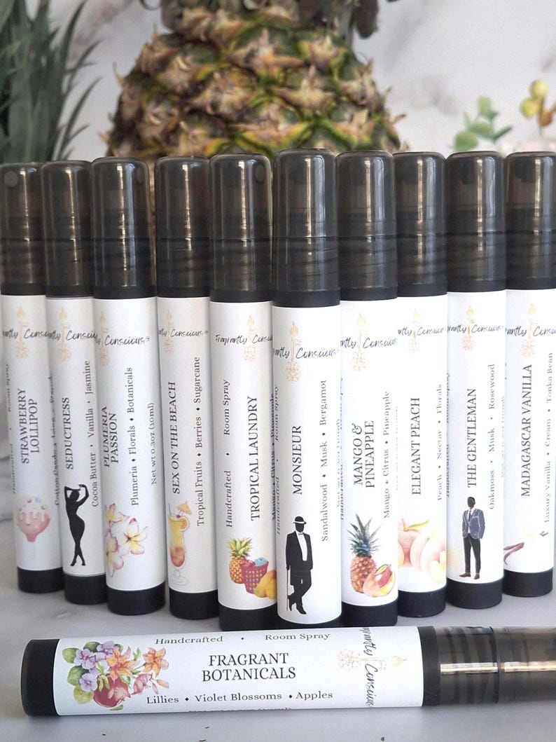 Puede incluir: Una colecci&oacute;n de diez aerosoles ambientales cil&iacute;ndricos con tapas negras y etiquetas blancas. Cada etiqueta presenta un dise&ntilde;o &uacute;nico y un nombre de aroma, como "Tropical Laundry" y "Mango & Pineapple". El aerosol inferior dice "Fragrant Botanicals".