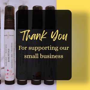 Puede incluir: Varios frascos de spray ambiental con tapas negras y etiquetas blancas. Las etiquetas muestran el texto "BLUEBERRY JUBILEE" y "ROSE PETALS". Un cuadrado negro con texto amarillo dice "Thank You For supporting our small business."