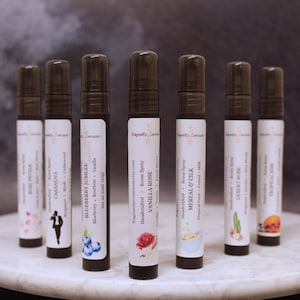 Puede incluir: Una variedad de ambientadores en botellas de vidrio transparente con tapas negras. Cada botella tiene una etiqueta blanca con el nombre de la marca y la descripci&oacute;n de la fragancia. Los aromas incluyen Rose Petals, Casanova, Blueberry Jubilee, Vanilla Rose, entre otros. Las botellas est&aacute;n dispuestas sobre una superficie de m&aacute;rmol blanco.
