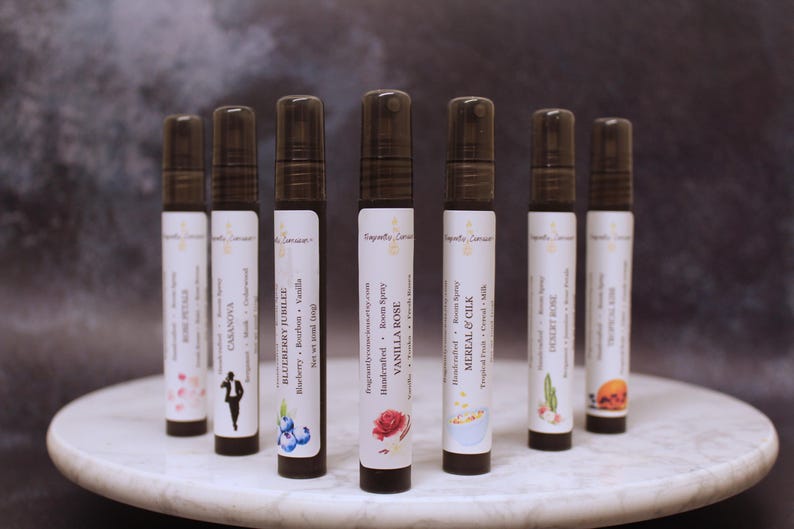 Puede incluir: Una variedad de ambientadores en botellas de vidrio transparente con tapas negras. Cada botella tiene una etiqueta blanca con el nombre de la marca y la descripci&oacute;n de la fragancia. Los aromas incluyen Rose Petals, Casanova, Blueberry Jubilee, Vanilla Rose, entre otros. Las botellas est&aacute;n dispuestas sobre una superficie de m&aacute;rmol blanco.