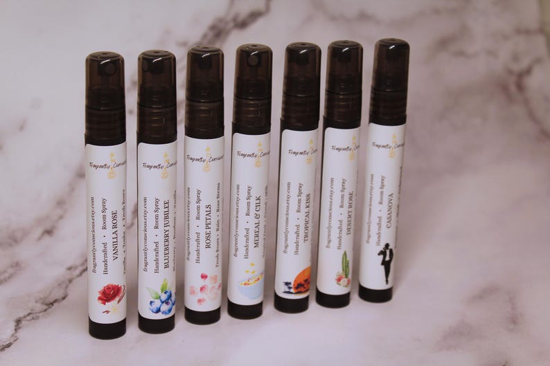 Puede incluir: Siete botellas de spray para habitaciones con tapas negras y etiquetas blancas. Las etiquetas presentan varias ilustraciones florales y frutales, incluyendo una rosa, ar&aacute;ndanos y un cactus. Las botellas est&aacute;n etiquetadas con aromas como Vanilla Rose, Blueberry Jubilee y Desert Rose.
