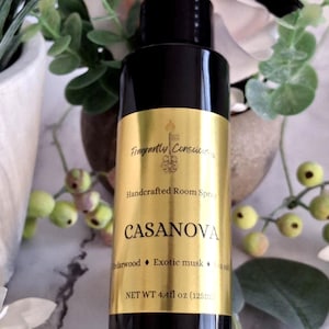 May include: Black room spray bottle with a gold label. The label reads "Fragrant Conscious" and "CASANOVA". The bottle contains 4.4 fl oz (125ml) of room spray. The spray includes cedarwood, exotic musk, and sea salt.