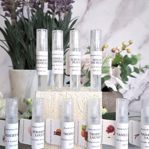 May include: Clear glass perfume sample bottles with white labels. Scents include "Fragrant Botanicals", "Cuddles Cashmere", "Elegant Peach", "Sex on the Beach", "Desert Rose", "Strawberry Lollie", "Tropical Fruit", "Tropical Laundry", "Vanilla", and "Madame Vanilla".