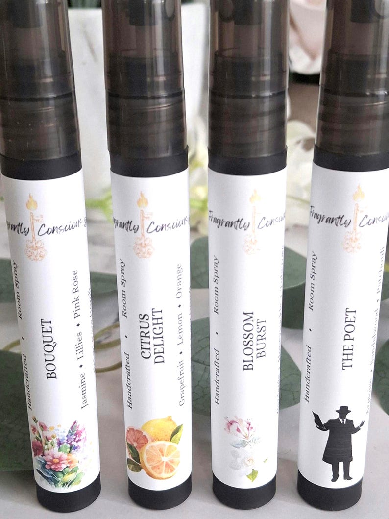 Puede incluir: Cuatro botellas de spray ambiental con tapas negras y etiquetas blancas. Las etiquetas presentan el texto "Fragrant Conscious" y los nombres "Bouquet", "Citrus Delight", "Blossom Burst" y "The Poet". Cada etiqueta tiene un dise&ntilde;o floral o gr&aacute;fico &uacute;nico.