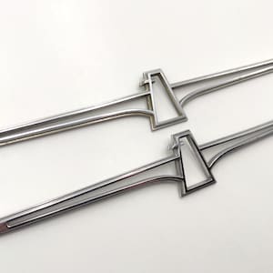 Puede incluir: Dos emblemas de coche de metal plateado en forma de pájaro con una envergadura de aproximadamente 25 cm. Los emblemas están hechos de un metal delgado y tienen un acabado brillante.