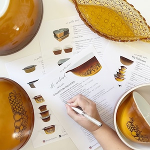 Może przedstawiać: Kolekcja vintage misek do mieszania i naczyń do zapiekania Pyrex w wzorze Old Orchard. Miski mają brązowo-biały wzór winogron z złotą obwódką. Kolekcja zawiera 4-częściowy zestaw misek do mieszania i miskę Kopciuszka.