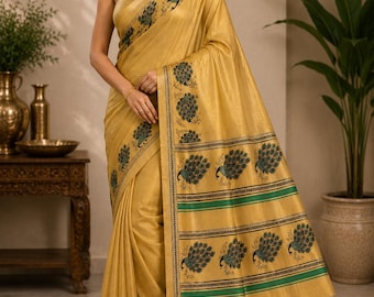 May include: A golden yellow saree featuring a repeating peacock motif in dark green and blue. The fabric has a subtle sheen, and the border is decorated with horizontal green stripes and rows of peacock illustrations along the entire length.