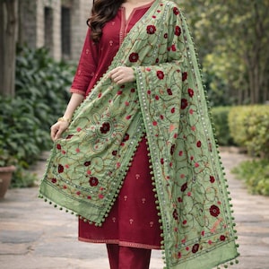 Könnte beinhalten: Burgunderfarbenes Salwar-Kameez-Ensemble mit passendem Dupatta. Das Dupatta ist hellgrün mit roten Blumenstickereien und grünen Bommelborten. Das Outfit wird im Freien getragen.