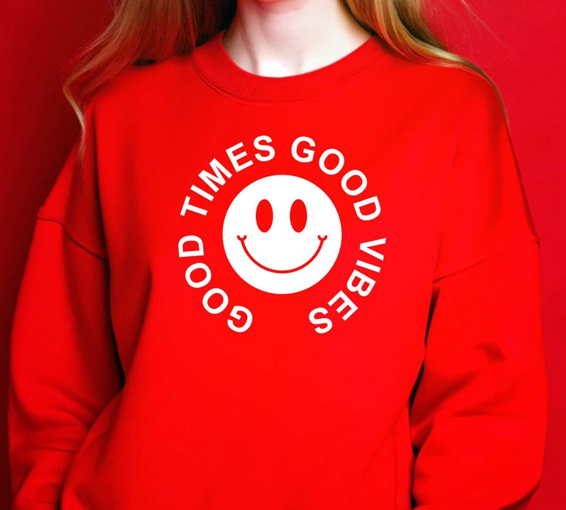 May include: A red sweatshirt with a white smiley face graphic and the words "GOOD TIMES GOOD VIBES" in a circular design. The sweatshirt is a solid red color and has long sleeves.