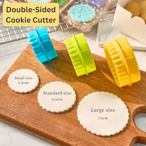 May include: A set of three double-sided cookie cutters in blue, green, and yellow, with scalloped edges. The image shows three sizes: small (5.5cm), standard (6.5cm), and large (7.5cm), along with the text "Double-Sided Cookie Cutter."