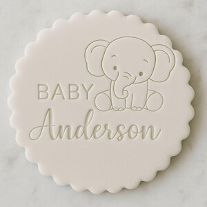 K&ouml;nnte beinhalten: Eine runde, cremefarbene Babyank&uuml;ndigung mit einem gewellten Rand. Das Design zeigt einen Cartoon-Elefanten und den Text "BABY Anderson". Das Design ist schlicht und elegant f&uuml;r eine Babyank&uuml;ndigung.