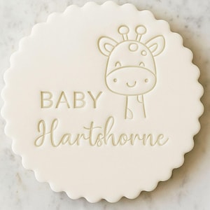 K&ouml;nnte beinhalten: Runde, cremefarbene Babyparty-Dekoration mit gewelltem Rand. Das Design zeigt eine Giraffenillustration und die Worte "BABY Hartshorne" in hellem Beige.