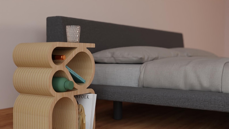 May include: A wooden bedside table with a unique, curved design. The table has multiple shelves and compartments for storage. It is next to a gray bed with white bedding.