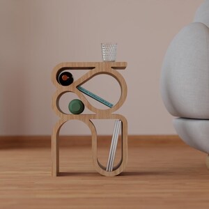 May include: A wooden side table with a unique, abstract design. The table has multiple shelves and curves, and is made of light brown wood. It is decorated with a green ball, a blue book, and a clear glass.
