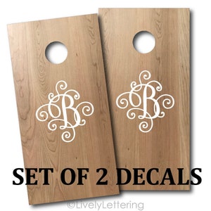 May include: Set of two white vinyl decals featuring a monogram with the letter "B" in a decorative script font. The decals are shown on a wooden surface. The text "SET OF 2 DECALS" is printed below the decals.
