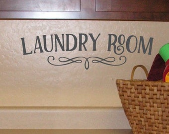 Könnte beinhalten: Eine Waschküchenszene mit einem geflochtenen Korb mit Waschutensilien. An der Wand steht in dekorativer Schrift "LAUNDRY ROOM". Die Schränke sind dunkelbraun und die Arbeitsplatte hellbeige.