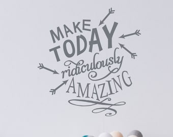Könnte beinhalten: Ein grauer Wandaufkleber mit dem Schriftzug "MAKE TODAY ridiculously AMAZING" in einer dekorativen Schriftart, mit Pfeilen, die auf den Text zeigen. Unter dem Text befindet sich ein Drahtkorb mit bunten Bällen, davor ein kleines Holzflugzeug.