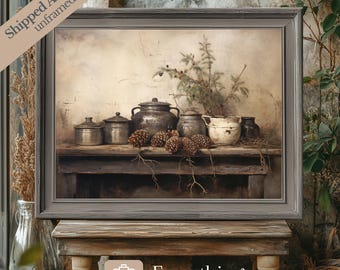 May include: A framed print of a still life featuring a collection of vintage metal pots and a small evergreen tree on a rustic wooden table. The pots are arranged in a row with pine cones scattered around them. The background is a faded beige wall.