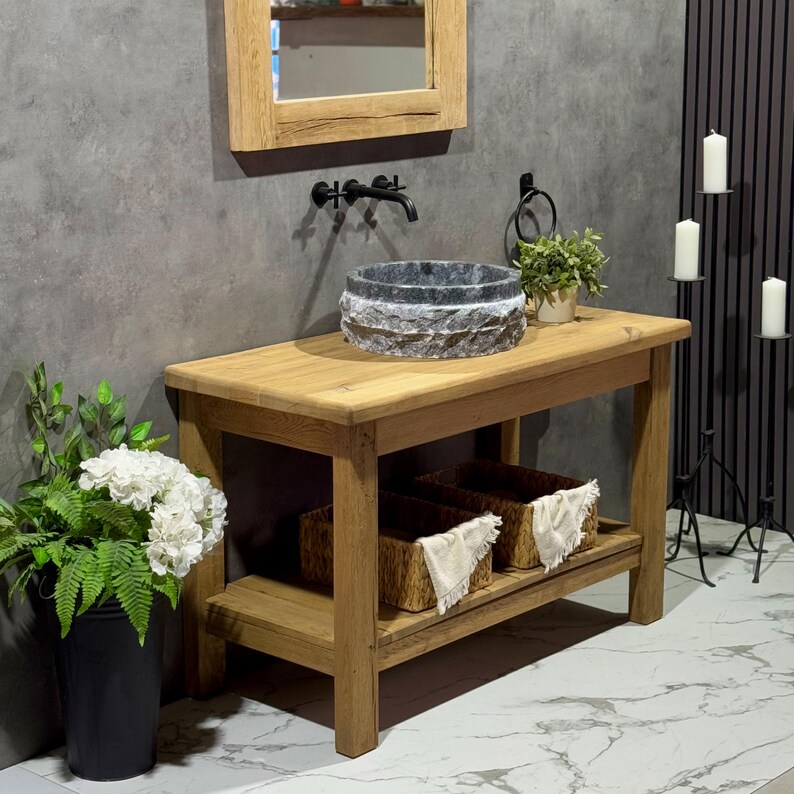 May include: A rustic wooden bathroom vanity with a stone sink and two woven baskets on the lower shelf. The vanity is made of reclaimed wood and has a natural finish.