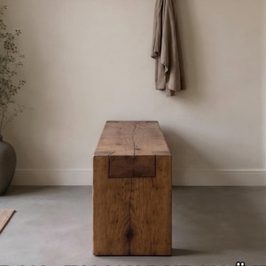 May include: A rectangular wooden bench crafted from a single block of timber with a visible grain pattern and a prominent vertical crack running along the top surface. The bench features a blocky, solid construction with visible joinery details.