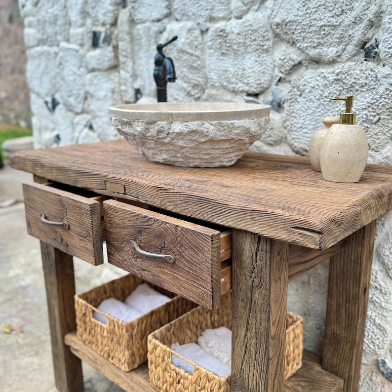 May include: A rustic wooden vanity with two drawers and a lower shelf. The vanity has a stone sink with a faucet and two soap dispensers.